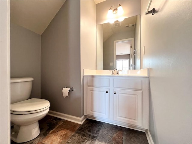 bathroom featuring vanity, lofted ceiling, and toilet