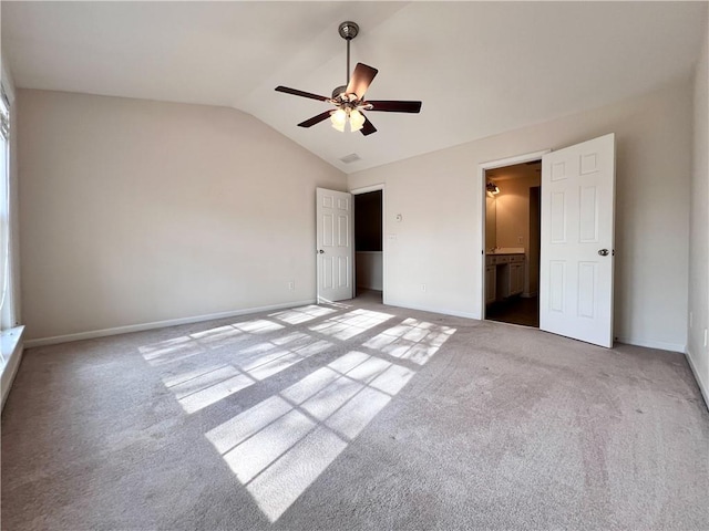 unfurnished bedroom with ensuite bath, lofted ceiling, carpet, and ceiling fan