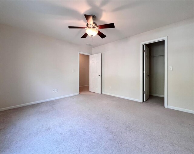 unfurnished bedroom featuring a closet, ceiling fan, a spacious closet, and light colored carpet