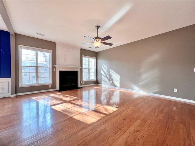 unfurnished living room with a large fireplace, a healthy amount of sunlight, and light hardwood / wood-style flooring