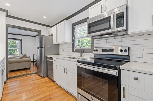 kitchen featuring appliances with stainless steel finishes, light hardwood / wood-style flooring, crown molding, sink, and white cabinetry