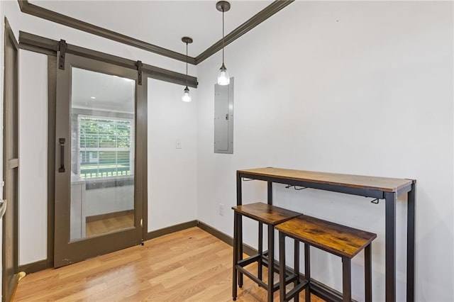 dining room with electric panel, a barn door, light hardwood / wood-style flooring, and ornamental molding