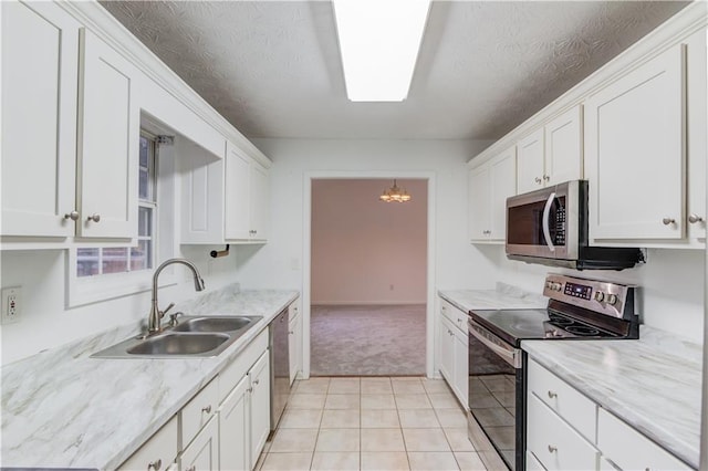 kitchen featuring a textured ceiling, a notable chandelier, stainless steel appliances, a sink, and white cabinetry