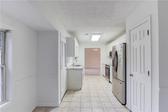 kitchen with white cabinets, stainless steel appliances, a sink, and light countertops