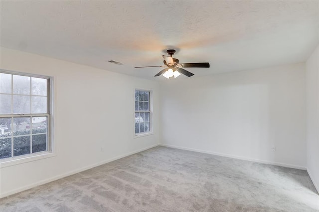 spare room with a textured ceiling, carpet flooring, visible vents, and baseboards