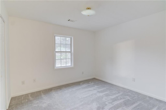 carpeted spare room featuring visible vents and baseboards