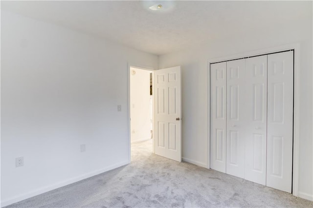 unfurnished bedroom with a closet, carpet, and baseboards