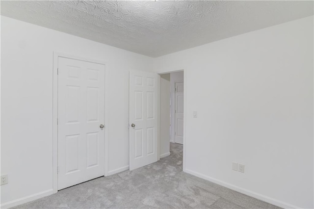 unfurnished bedroom with a textured ceiling, carpet, and baseboards