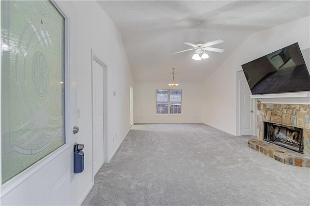 unfurnished living room with carpet floors, a ceiling fan, vaulted ceiling, a stone fireplace, and baseboards