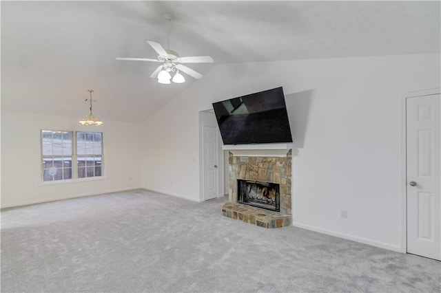 unfurnished living room featuring baseboards, vaulted ceiling, a stone fireplace, carpet floors, and ceiling fan with notable chandelier