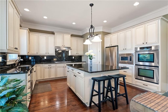 kitchen with backsplash, a center island, under cabinet range hood, appliances with stainless steel finishes, and a sink