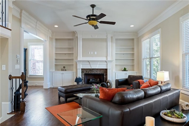 living area with built in features, recessed lighting, a fireplace, dark wood-style flooring, and crown molding