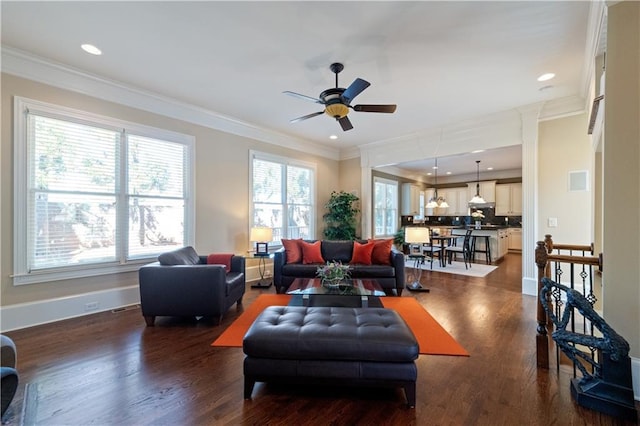 living room with a wealth of natural light, ornamental molding, and dark wood-style flooring