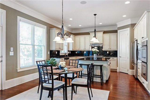 kitchen featuring dark wood finished floors, dark countertops, ornamental molding, and a kitchen island