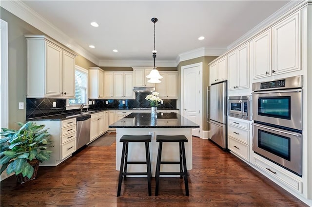 kitchen featuring a center island, under cabinet range hood, a breakfast bar, appliances with stainless steel finishes, and dark wood-style flooring