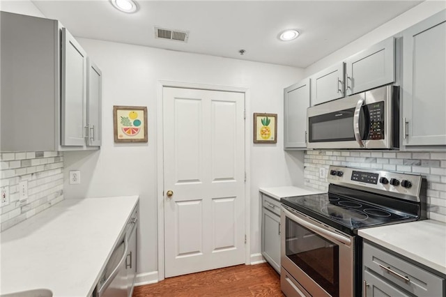 1101 Juniper St NE Unit 415, Atlanta, GA 30309 - kitchen featuring stainless steel appliances, gray cabinetry, decorative backsplash, dark wood-style flooring, and recessed lighting