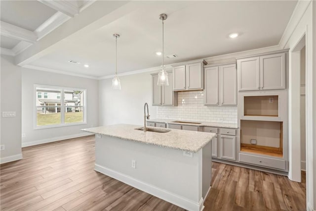 kitchen featuring light stone counters, wood-type flooring, pendant lighting, gray cabinetry, and sink