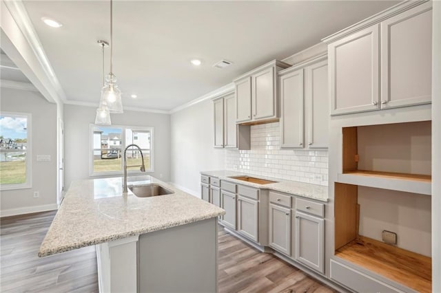 kitchen featuring sink, light stone counters, gray cabinetry, and a healthy amount of sunlight