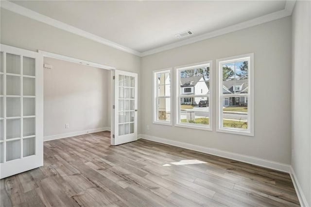 unfurnished room with french doors, ornamental molding, and light wood-type flooring