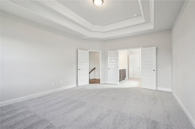 unfurnished bedroom featuring light carpet and a raised ceiling