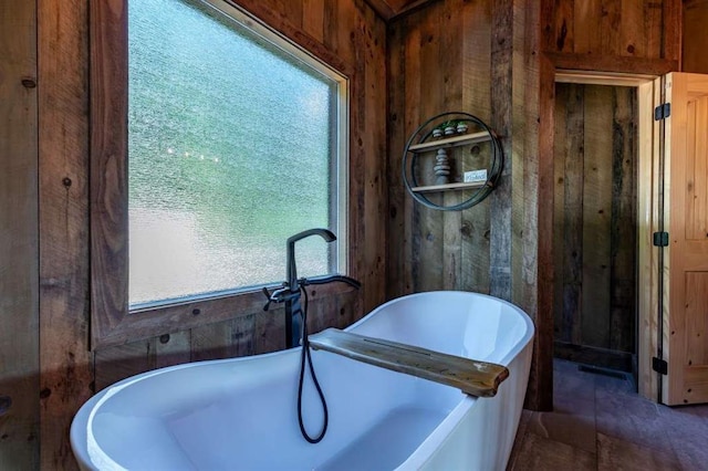 bathroom featuring tile patterned floors, a washtub, and wood walls