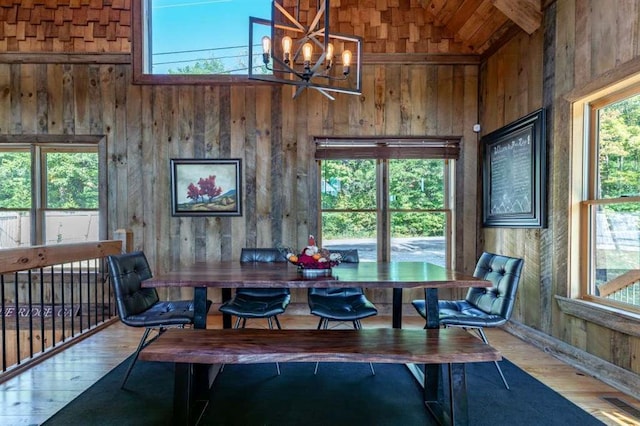 dining room with hardwood / wood-style flooring, a notable chandelier, and wood walls