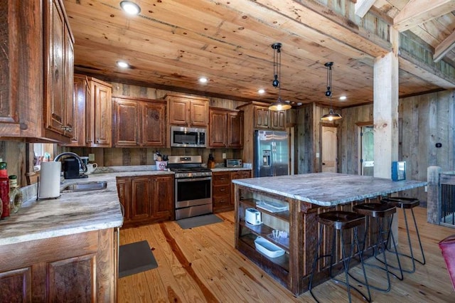 kitchen featuring light wood-type flooring, stainless steel appliances, sink, decorative light fixtures, and a kitchen island