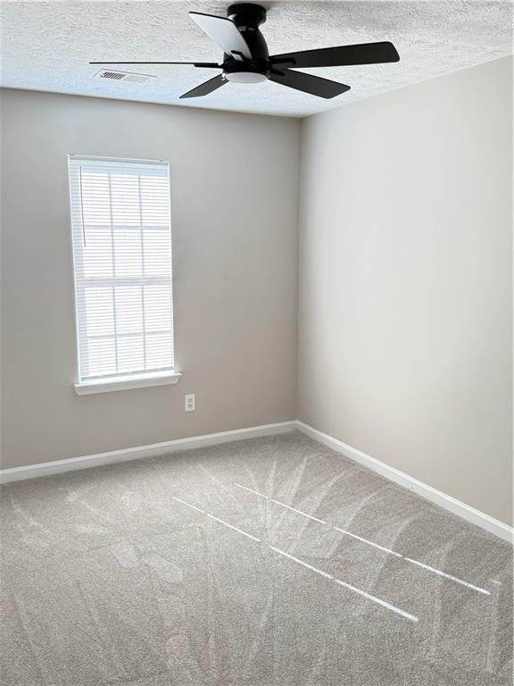 2115 Charter Ln, Lithonia, GA 30058 - carpeted empty room featuring a textured ceiling, visible vents, a ceiling fan, and baseboards