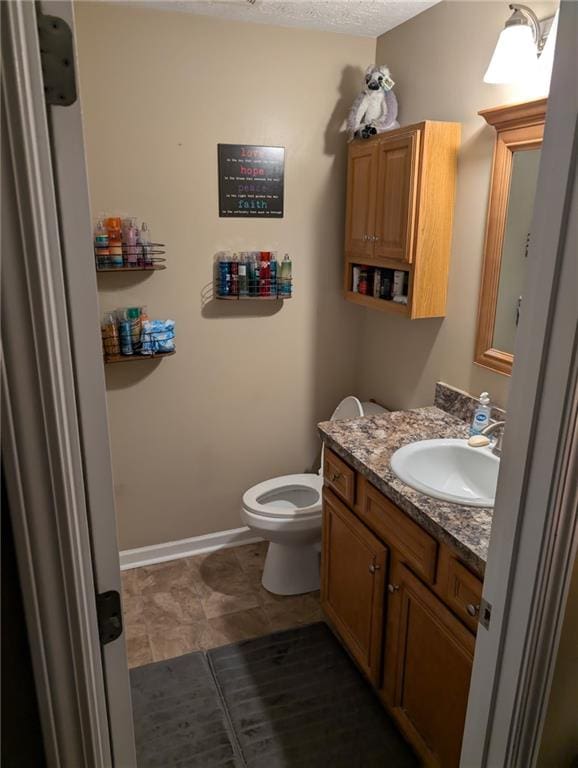 half bath featuring vanity, baseboards, and toilet