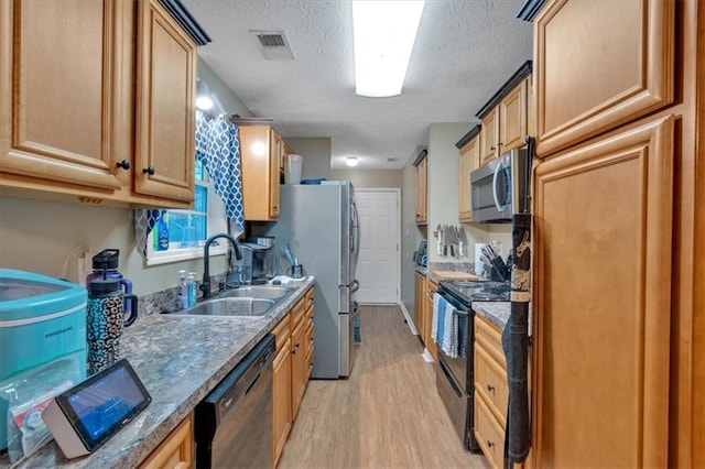 kitchen featuring visible vents, light wood-type flooring, a textured ceiling, a sink, and black appliances