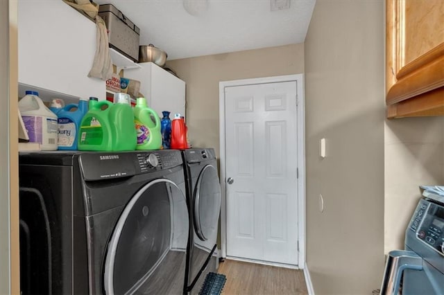 laundry room featuring washer and dryer, cabinet space, and wood finished floors