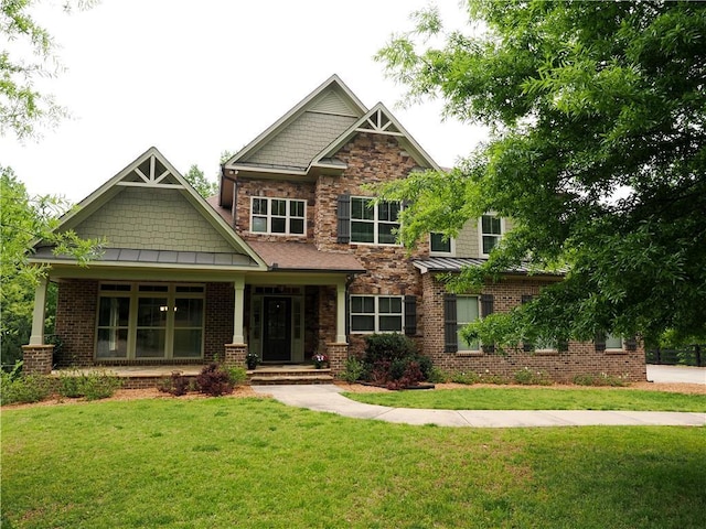 craftsman-style home featuring a standing seam roof, a front yard, metal roof, and stone siding