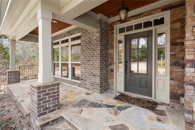 doorway to property featuring covered porch and brick siding