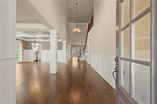 entrance foyer with a chandelier, a decorative wall, dark wood-style floors, ornamental molding, and a wainscoted wall