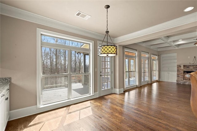 unfurnished dining area featuring coffered ceiling, wood finished floors, baseboards, beam ceiling, and a stone fireplace