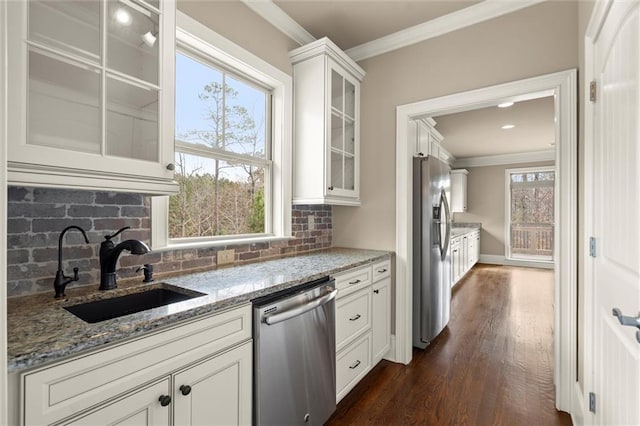 kitchen featuring stainless steel appliances, a sink, crown molding, backsplash, and dark wood-style flooring