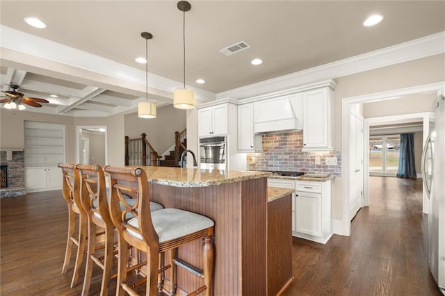 kitchen with premium range hood, stainless steel oven, ceiling fan, coffered ceiling, and tasteful backsplash