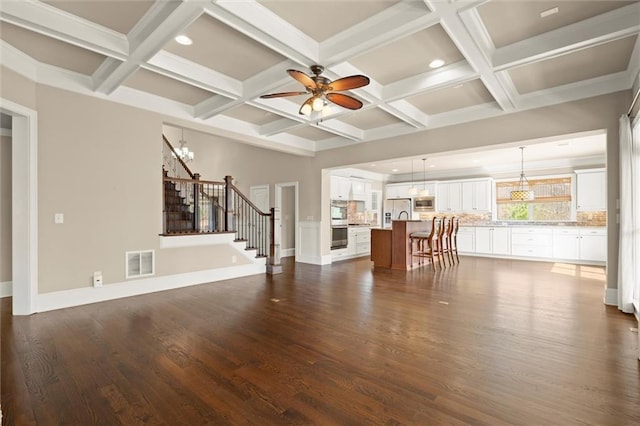 living area featuring a ceiling fan, coffered ceiling, stairway, beamed ceiling, and dark wood-type flooring