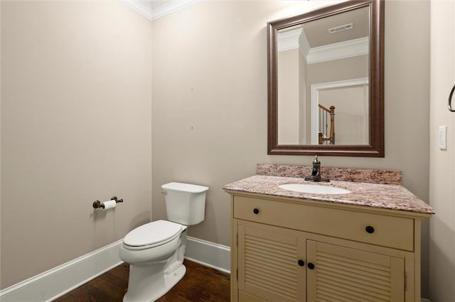 half bath featuring crown molding, baseboards, wood finished floors, vanity, and toilet
