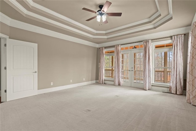 empty room with a raised ceiling, ornamental molding, carpet, french doors, and ceiling fan