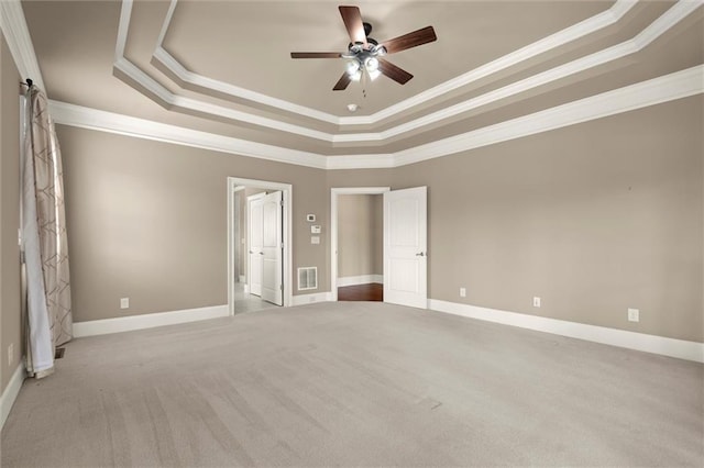 unfurnished bedroom featuring carpet flooring, crown molding, a raised ceiling, baseboards, and ceiling fan