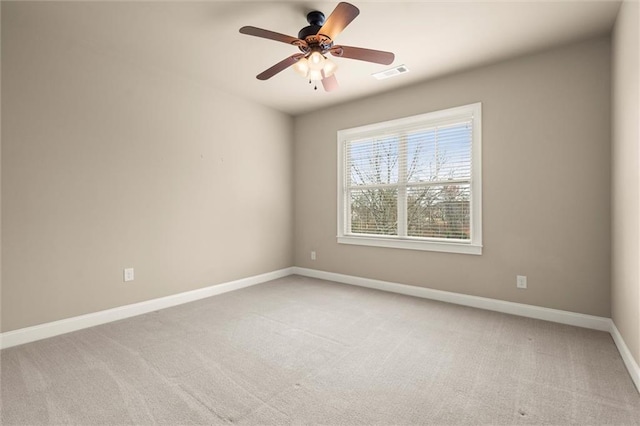 unfurnished room featuring light colored carpet, a ceiling fan, and baseboards