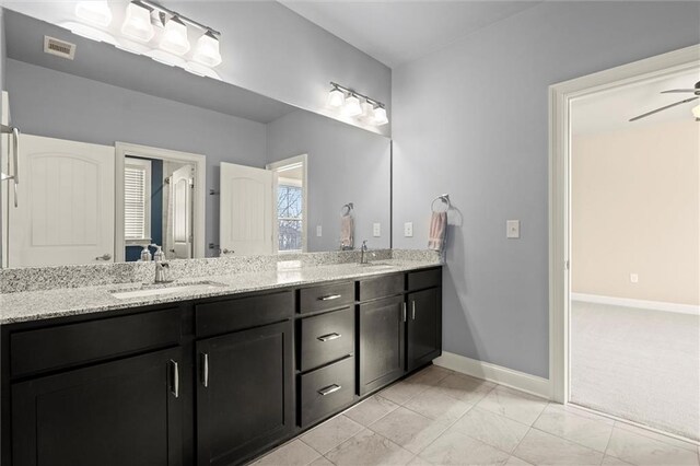 bathroom with baseboards, double vanity, and ceiling fan