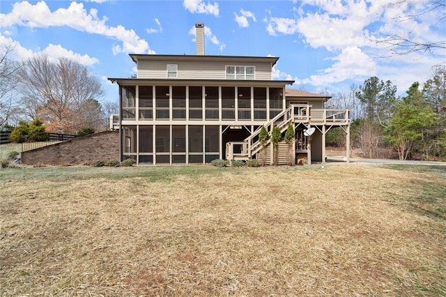 rear view of property with a sunroom, stairs, a chimney, a wooden deck, and a yard