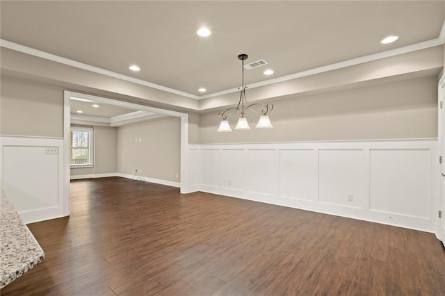 spare room with ornamental molding, dark wood-style flooring, a decorative wall, and a wainscoted wall