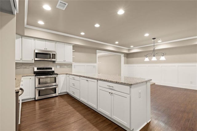 kitchen featuring stainless steel appliances, open shelves, crown molding, a peninsula, and a wainscoted wall