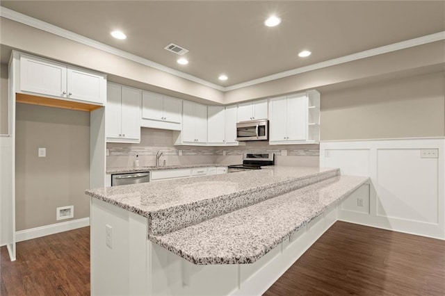 kitchen with appliances with stainless steel finishes, crown molding, open shelves, a peninsula, and white cabinetry