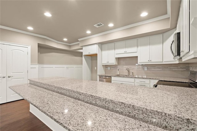 kitchen featuring appliances with stainless steel finishes, ornamental molding, a sink, light stone countertops, and white cabinetry