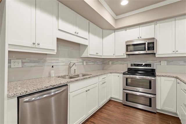 kitchen featuring appliances with stainless steel finishes, a sink, crown molding, white cabinetry, and backsplash