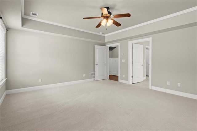 unfurnished bedroom with light carpet, crown molding, baseboards, a ceiling fan, and a spacious closet
